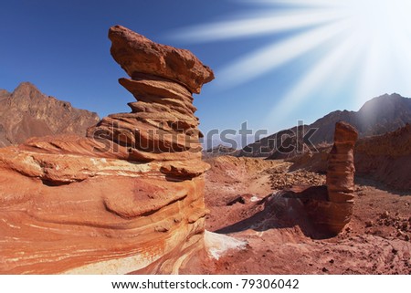 The sparkling sun above interesting natural forms of sandstone hoodoos in mountains of Eilat, Israel