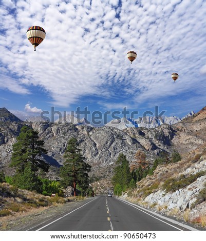 Huge balloons with the passenger basket flying over the magnificent American road in the mountains