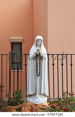 The sculptural image of Maiden Maria with beads in hands. A white sculpture.