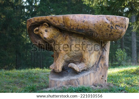 Wooden table made from single piece with carved bear figure