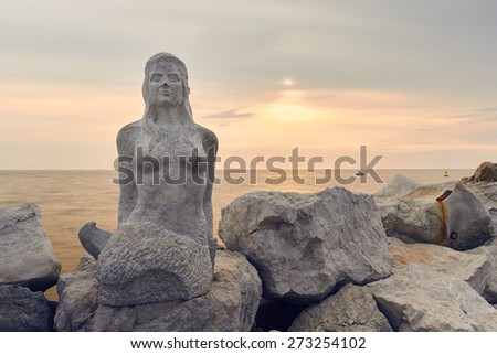 PIRAN - APRIL 18: Late afternoon portrait of beautiful stone mermaid statue on the rocky coastline on April 18, 2015 in  Piran, Slovenia, Europe.