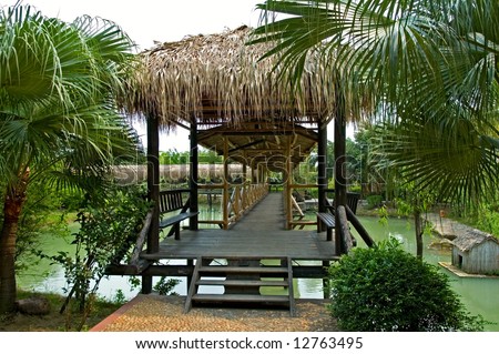 The wooden walk bridge over lake in garden with trees and bushes