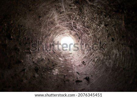 Dirty dark tube interior with light in the end, fallen int deep well pit Imagine de stoc © 