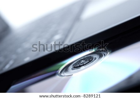 Laptop with a CD or  DVD in the tray (shallow depth of field, focus is on the middle of the cd tray)