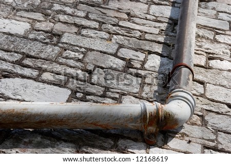 Weathered channel pipe on a gray stone wall
