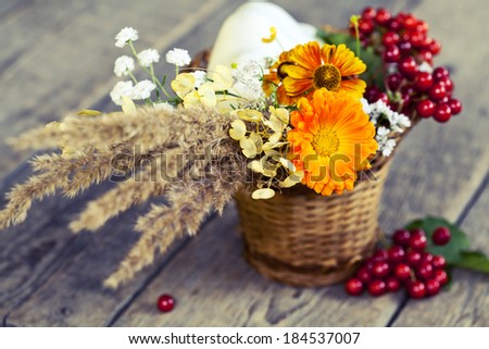 Bouquet of autumn flowers and berries in basket, toned