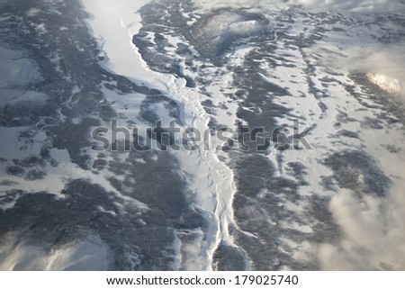 Majestic aerial view of frozen Northern Sweden. High mountain ranges and frozen rivers and lakes with low clouds.