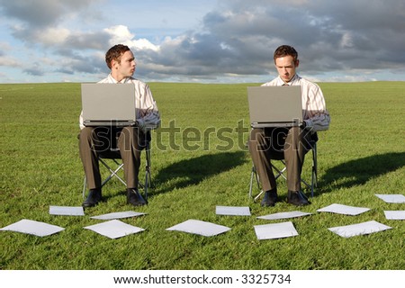 Two businessmen on Laptops in a field.