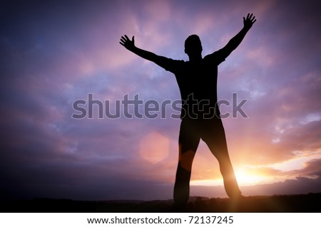 Open Dreams - A man standing with open arms set against a beautiful sunrise.