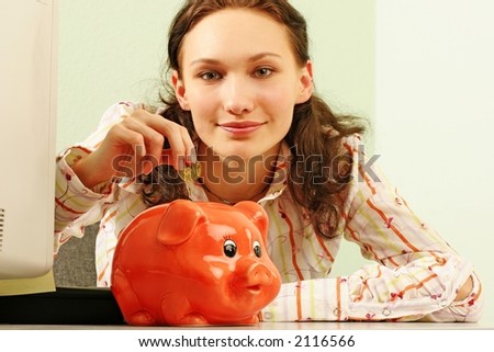 saving money-young woman putting a coin into a red money-box