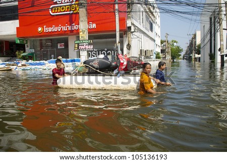 PATHUM THANI, THAILAND - OCT 27: Thai residents moving a motorcycle through a flooded road in Pathum Thani near Bangkok, Thailand on October 27, 2011.