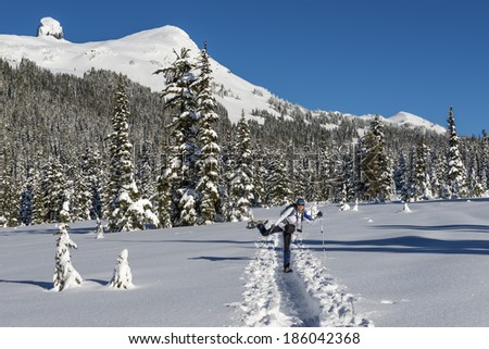 Happy woman snowshoeing in scenic winter landscape