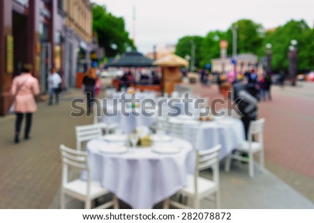 Buffet Restaurant with glasses on a white table cloth and chairs in the square of the old town. Blurry