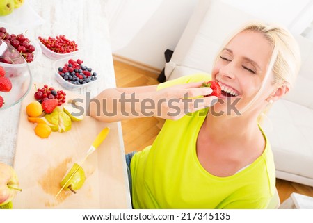 A beautiful mature woman eating strawberry at home.