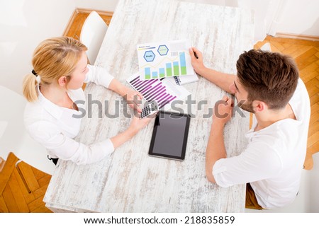 A young couple organizing their financial situation at home.