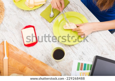 Young woman preparing breakfast while getting online information about nutrition.
