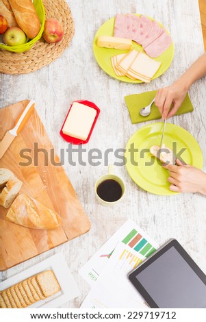 Young woman preparing breakfast while getting online information about nutrition.