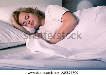 A plus size young woman sleeping in bed at night.