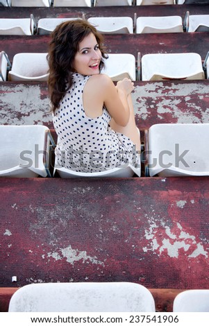 A vintage style emotional girl sitting in a sports stadium.