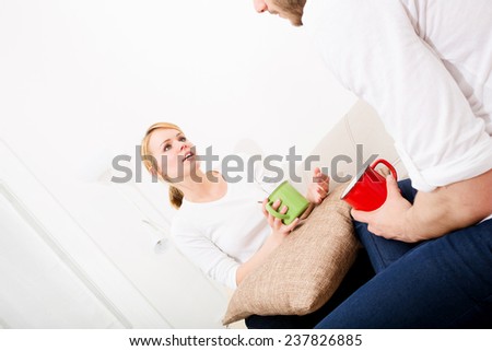 A young couple talking with coffee on the Sofa.