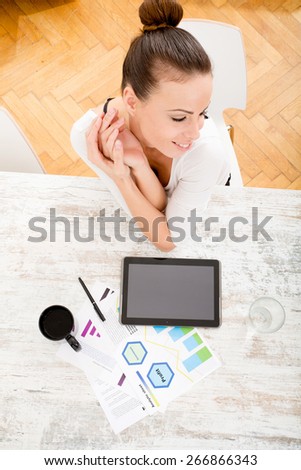 A young adult woman developing a business plan with her tablet PC at home.