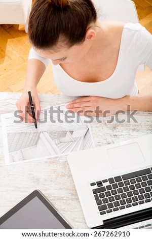 A young adult woman developing a architectural plan at home.