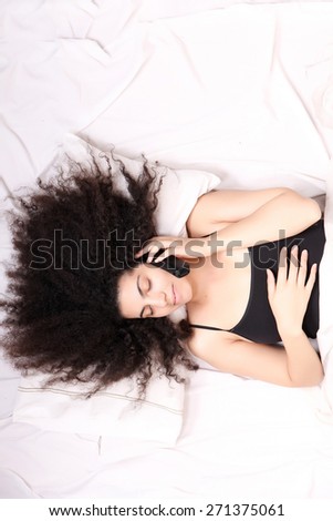A young latin woman dreaming and sleeping while hugging herself.