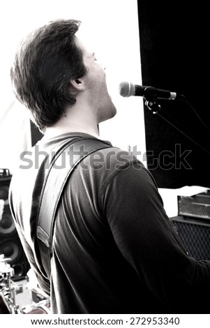 Black and white Portrait of a Rock singer playing bass in the rehearsal Studio.