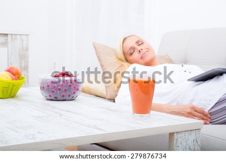 A mature woman in pyjamas sleeping with a tablet PC on the sofa.