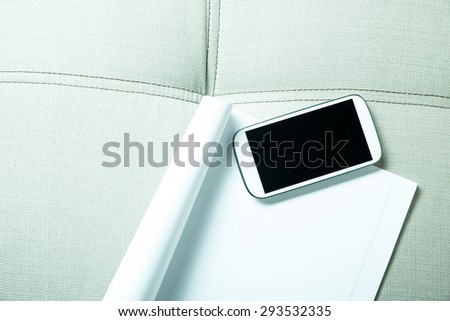 A smartphone and a exercise book lying on a sofa.