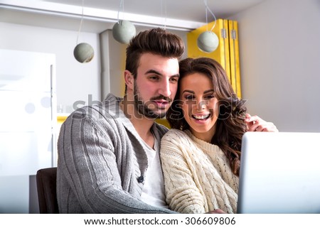 A young couple using in the evening their laptop computers at home.