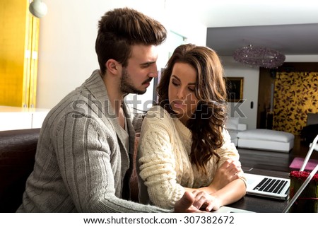 A young couple discussing a subject in the evening their laptop computers at home.