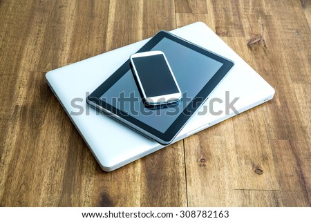 A Laptop computer, a Tablet PC and a Smartphone on a wooden Desktop.