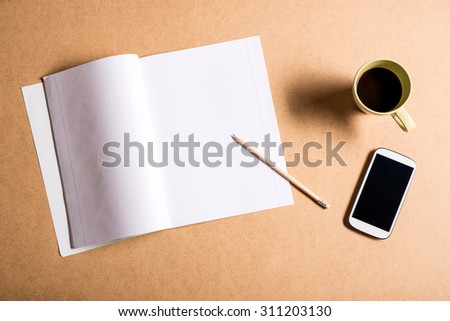 A smartphone and a exercise book on a wooden Desk.