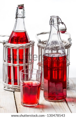 Closeup of red juice in vintage bottles on white background