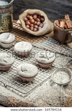 Closeup of falling powder sugar on fresh vanilla muffins
