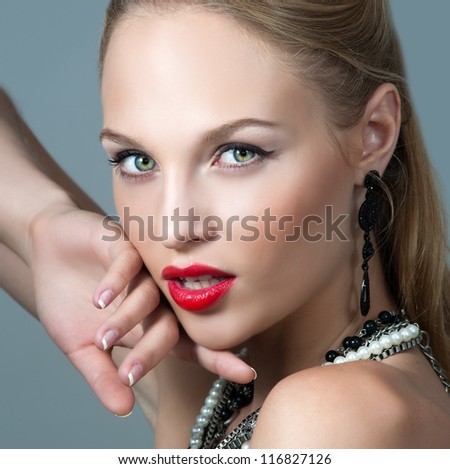 Young woman model with glamour red lips,bright makeup, eye arrow makeup, purity complexion with red lipstick. Beads.
