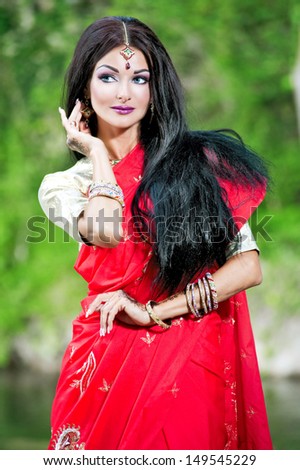 Beautiful young indian woman in traditional clothing with bridal makeup and jewelry. gorgeous brunette bride traditionally dressed Outdoors in India. Girl bollywood dancer in Sari and henna on hands