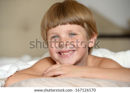 smiling boy in bed under the blanket