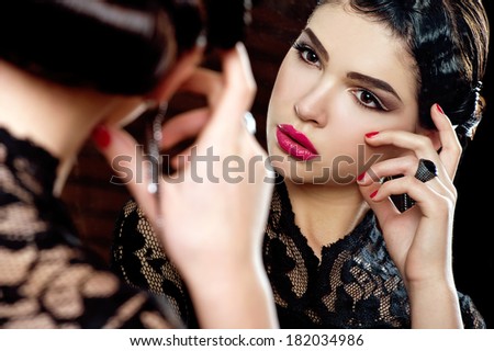 beautiful woman with trendy make-up in evening dress looks in the mirror