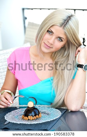 young blonde woman sitting in a cafe in with a cup of coffee latte and chocolate cake