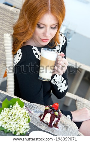 young woman sitting in a cafe in with a cup of coffee latte and chocolate cake