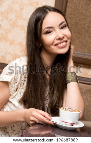 young woman sitting in a cafe in with a cup of coffee cappuccino