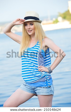 Beautiful sexy blonde woman wearing sailor striped dress posing near sea
