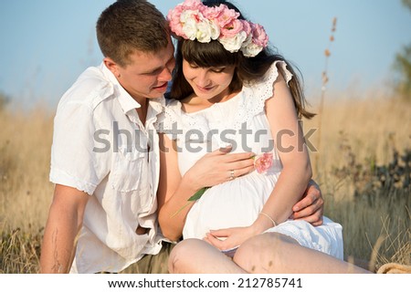 A pregnant beautiful woman with her husband resting outdoors in the summer