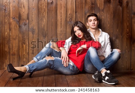 Beautiful sexy couple in love on wooden background dressed in blue jeans
