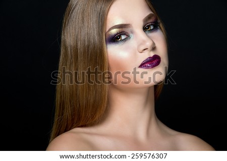 Closeup beauty portrait of attractive model face with bright visage. Multicolored eye makeup and vinous lips make-up