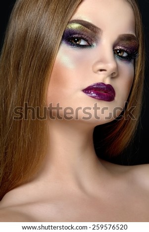 Closeup beauty portrait of attractive model face with bright visage. Multicolored eye makeup and vinous lips make-up