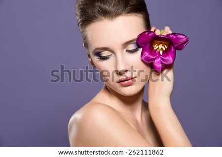 Close-up of beautiful woman face with colorful make-up and lips with bight flower. Woman with tulip.