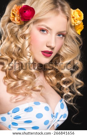 Beautiful blonde woman with perfect curly hair. Woman with bright make up and flowers in her hair.